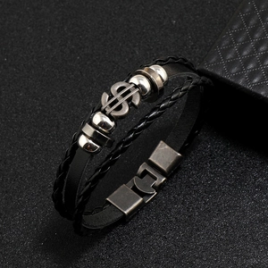 Macro detail of men's multilayer leather bracelet featuring silver dollar sign charm