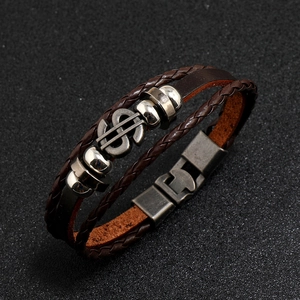 Detail view of multi-layer brown braided leather bracelet with silver dollar sign charm
