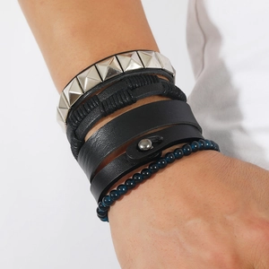 Close-up of men's multilayered black leather bracelets with pyramid studs and blue beads
