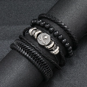Macro detail of men's multilayer black braided leather bracelets with pirate skull metal charm