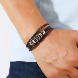 Detail of multi-layer leather bracelet with silver dollar sign and woven cord
