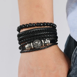 Detail of men's multilayer black braided leather bracelet with skull metal charm