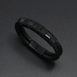 Dettaglio del bracciale in pelle nera intrecciata con cilindri metallici e fibbia magnetica