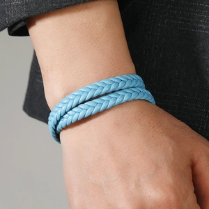 Detail shot of light blue woven leather double-wrap bracelet on a model wearing a suit