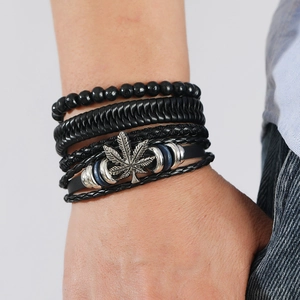 Close-up of men's layered leather bracelet featuring a silver hemp leaf charm on wrist