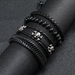 Macro shot of men's vintage black leather braided bracelets with skull charm on black stand