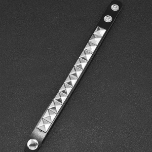 Detail of a black punk leather bracelet with silver pyramid studs and snap buttons