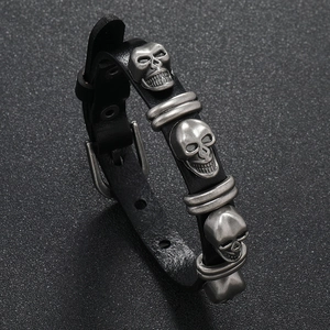 Detail view of punk leather bracelet featuring vintage silver skulls and ring hardware