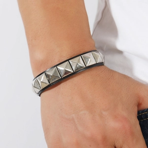 Close-up of a punk leather bracelet with square silver rivets worn on a male wrist