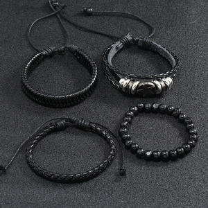 Detail of four-piece black leather braided bracelets with beads and metal charms