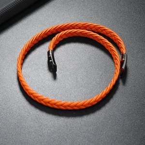 Detail view of bright orange braided leather bracelet with black magnetic metal clasp