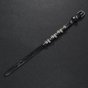 Detail of punk black leather bracelet with four silver metal skulls and buckle clasp