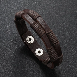 Macro detail of braided brown leather bracelet featuring silver metal snap button closure