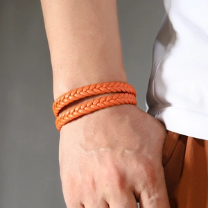 Close-up of vibrant orange double-wrap braided leather bracelet on a wrist