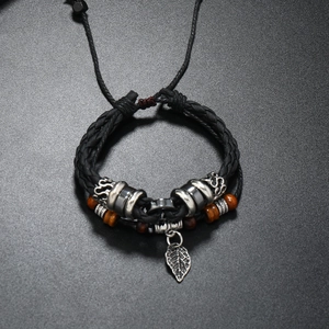 Macro shot of men's leather braided bracelet with wooden beads and silver leaf pendant