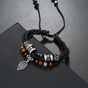 Detail of vintage woven leather bracelet with silver leaf pendant and wood beads