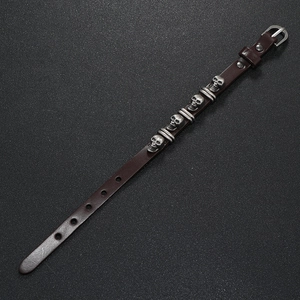 Close-up of vintage silver skull charms and rivets on dark brown punk leather bracelet