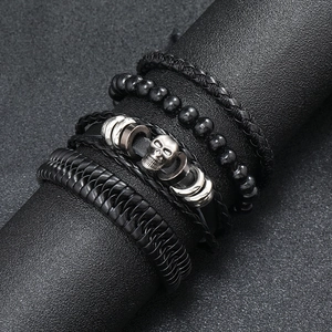 Macro detail of men's multilayer hand-woven leather bracelet set with silver skull charm