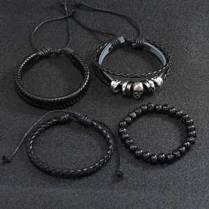 Detail view of four-piece set with black braided leather bracelets and skull charm