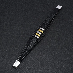 Detalle de pulsera de cuero trenzado multicapa con deslizadores de metal dorado y plateado