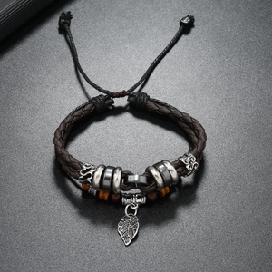 Detail of woven brown leather bracelet featuring a leaf pendant and adjustable knot closure