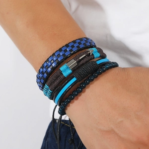 Close-up of men's layered leather bracelets with woven cords and arrow charm