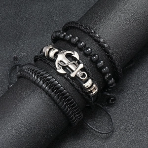 Macro view of four men's braided leather bracelets with a vintage silver anchor charm