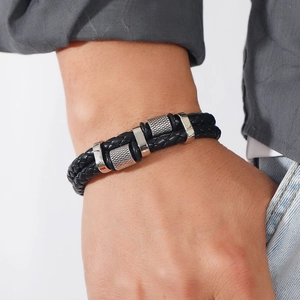 Close-up of a men's layered black braided leather bracelet with silver metal ring details
