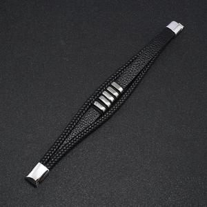 Detalle de una pulsera multicapa de cuero negro trenzado con cierre magnético plateado