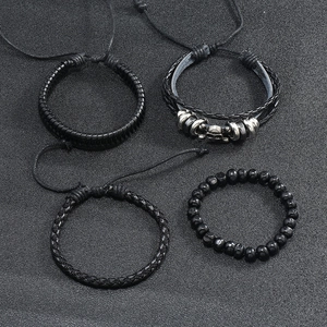 Detail of four-piece black leather bracelet set featuring skull metal and beaded strands