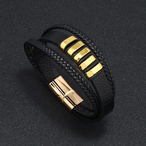 Detalle de pulsera multicapa de cuero negro trenzado con cierre magnético dorado pulido