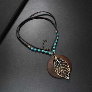 Collana boho con foglia di metallo cava e ciondolo rotondo in legno su cordino di cuoio