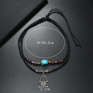 Detail of bohemian necklace with turquoise beads and Hamsa Hand pendant on black cord