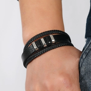 Primer plano de pulsera multicapa de cuero negro trenzado con cierre magnético en la muñeca