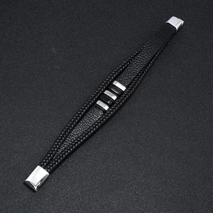 Detalle macro de pulsera de cuero negro multicapa con cierre de metal plateado pulido
