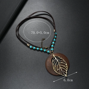 Dettaglio della collana boho con pendente in legno, foglia dorata e perla turchese