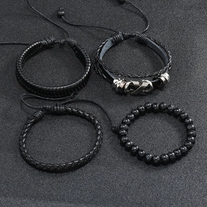 Macro view of 4-piece vintage black braided leather bracelet set with metal X charm