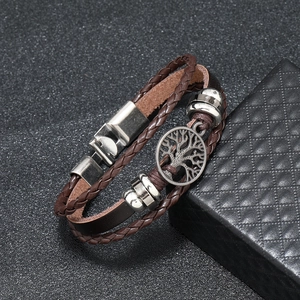 Detail view of multi-layer leather bracelet featuring a Tree of Life metal charm and gift box