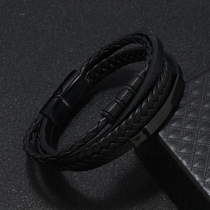 Detailed macro view of multi-layer black braided leather bracelet with magnetic metal clasp