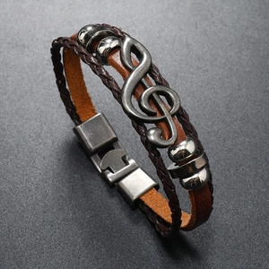 Detail view of vintage multi-layer leather bracelet with silver treble clef music charm