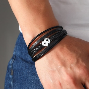 Detailansicht eines mehrlagigen Lederarmbands mit Fußball-Anhänger am Handgelenk