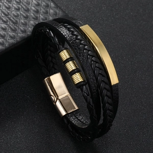 Macro shot of multi-layer black leather bracelet with gold rectangular plate and magnetic clasp