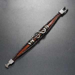Detail of multi-layer woven leather bracelet featuring an antique musical note charm