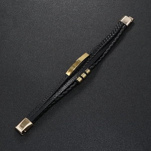 Detail of multi-layer black leather bracelet with golden metal accents and magnetic clasp