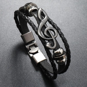Close-up of multilayer braided leather bracelet with silver treble clef music charm