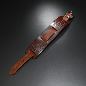 Close-up of brown leather punk bracelet with detailed wolf head embossed pattern