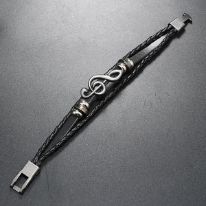 Close-up of multilayer leather bracelet with silver musical note charm and clasp