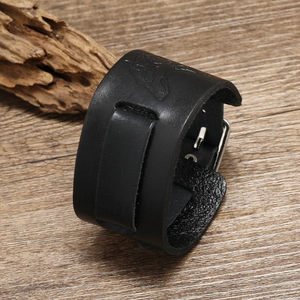 Detail of a vintage black leather punk wristband with metallic buckle on wooden background