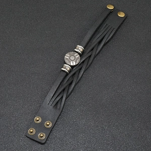 Detalle de la pulsera punk de cuero negro multicapa con adornos vintage y broches de presión