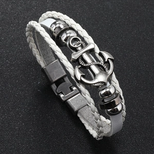 Macro detail of white multilayer braided leather bracelet with vintage metal anchor charm